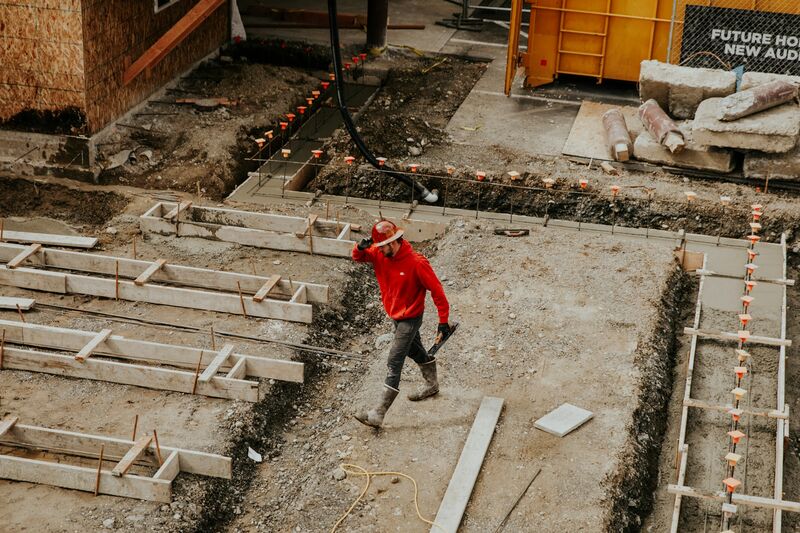 Avattu perustuskaivanto ja muottityötä rakennuksen ympärillä.